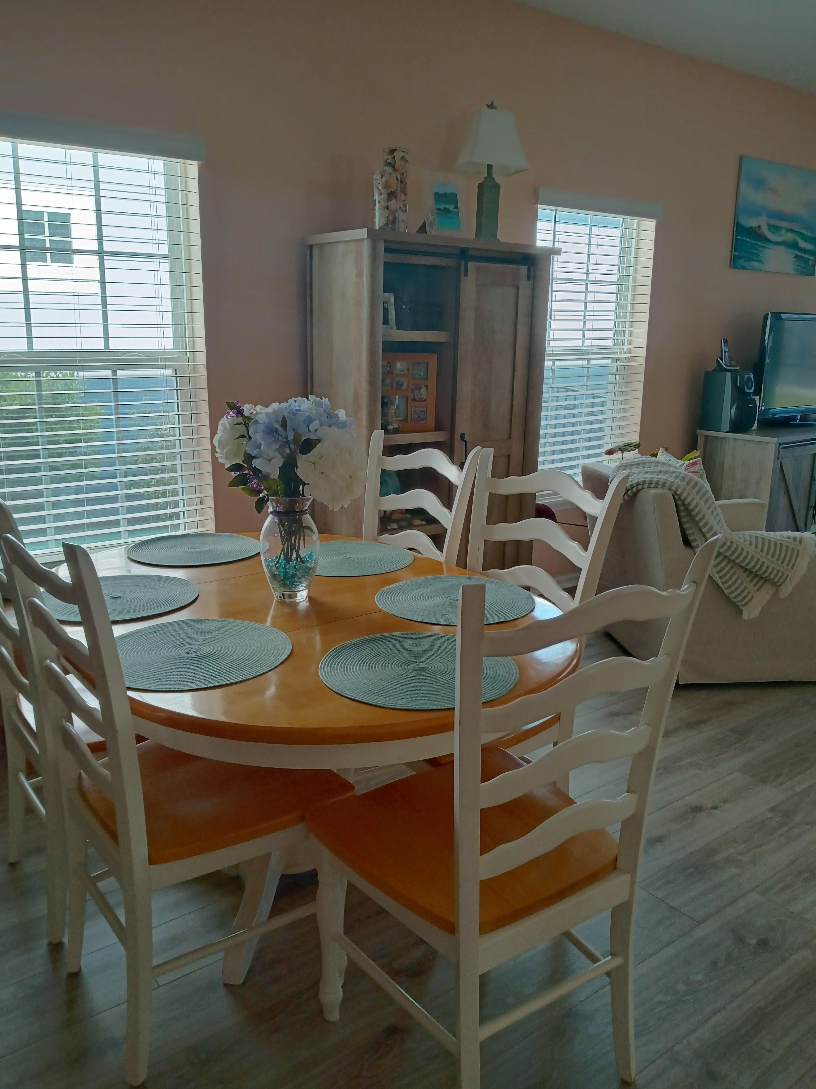 Dining room with white chairs, floral centerpiece, and coastal decor