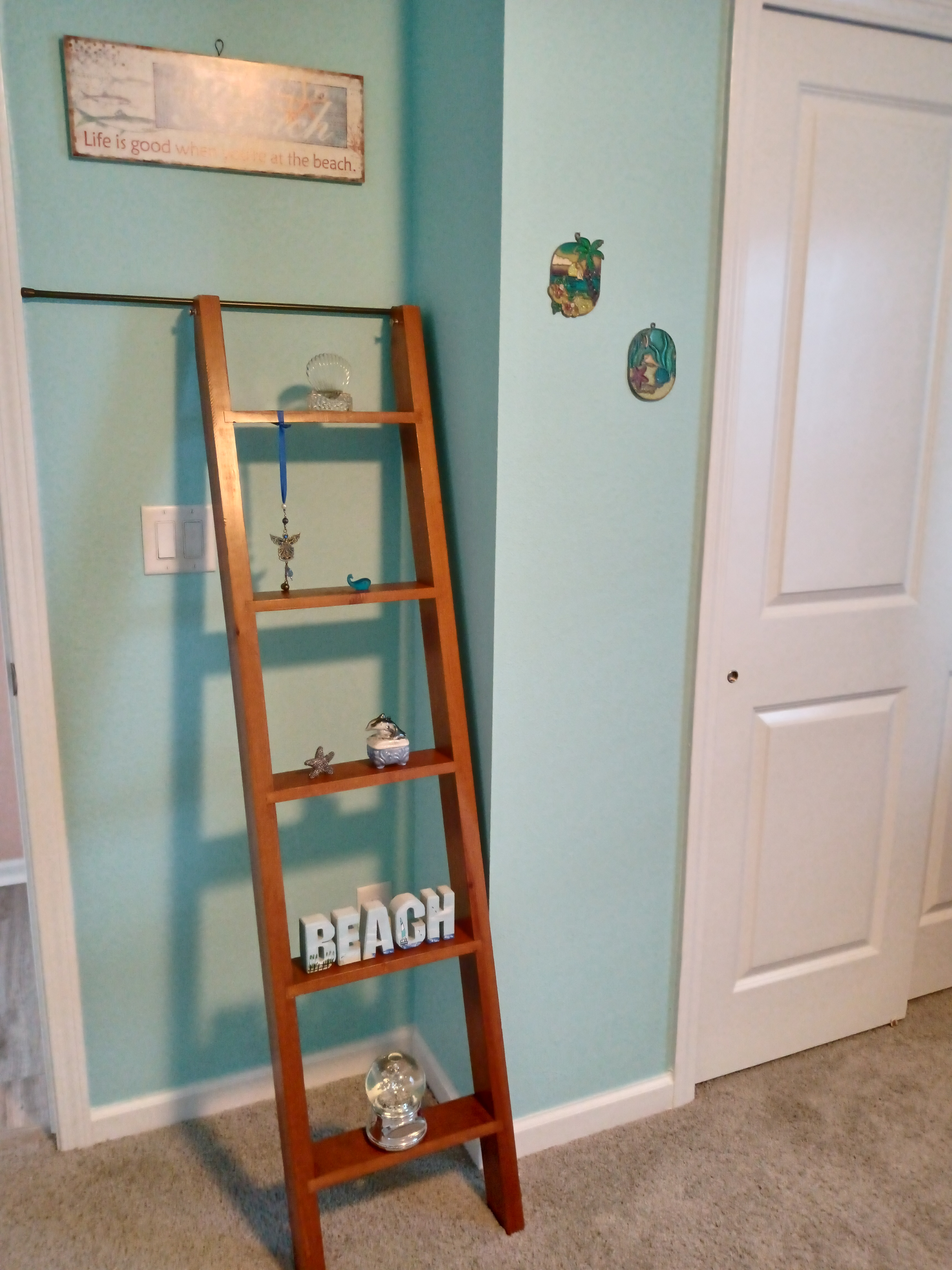 Beach-themed bedroom with ladder shelf and teal walls