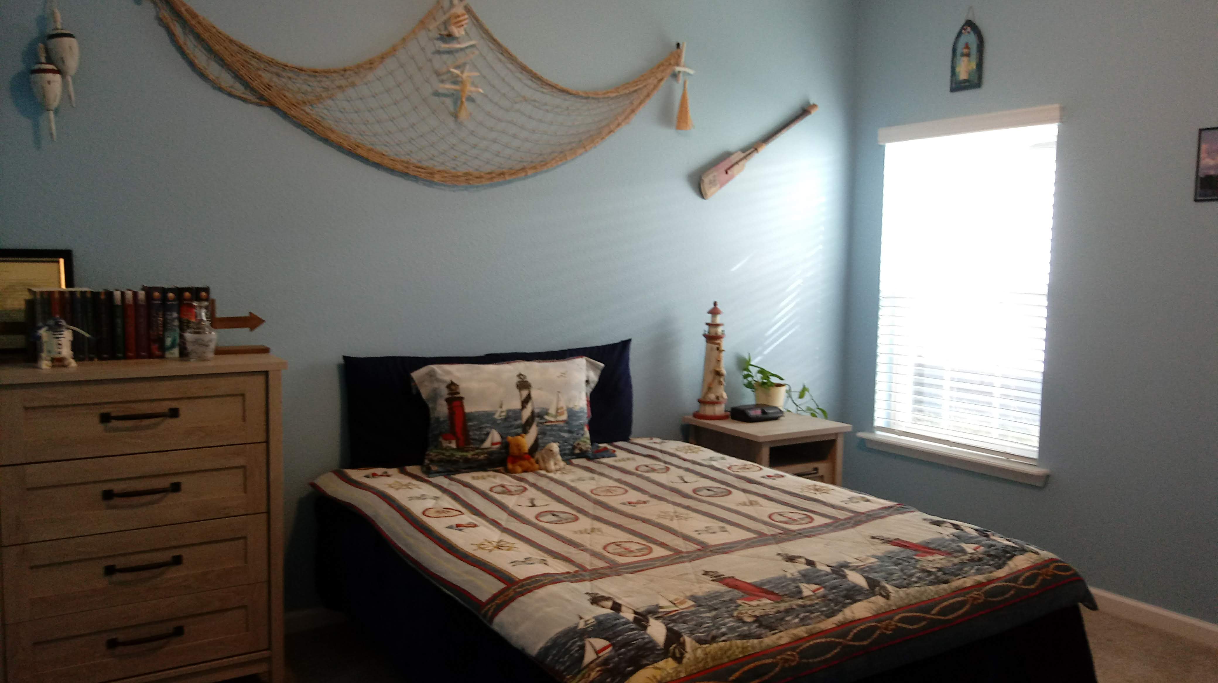 Coastal nautical bedroom with fish net wall decor and lighthouse accents