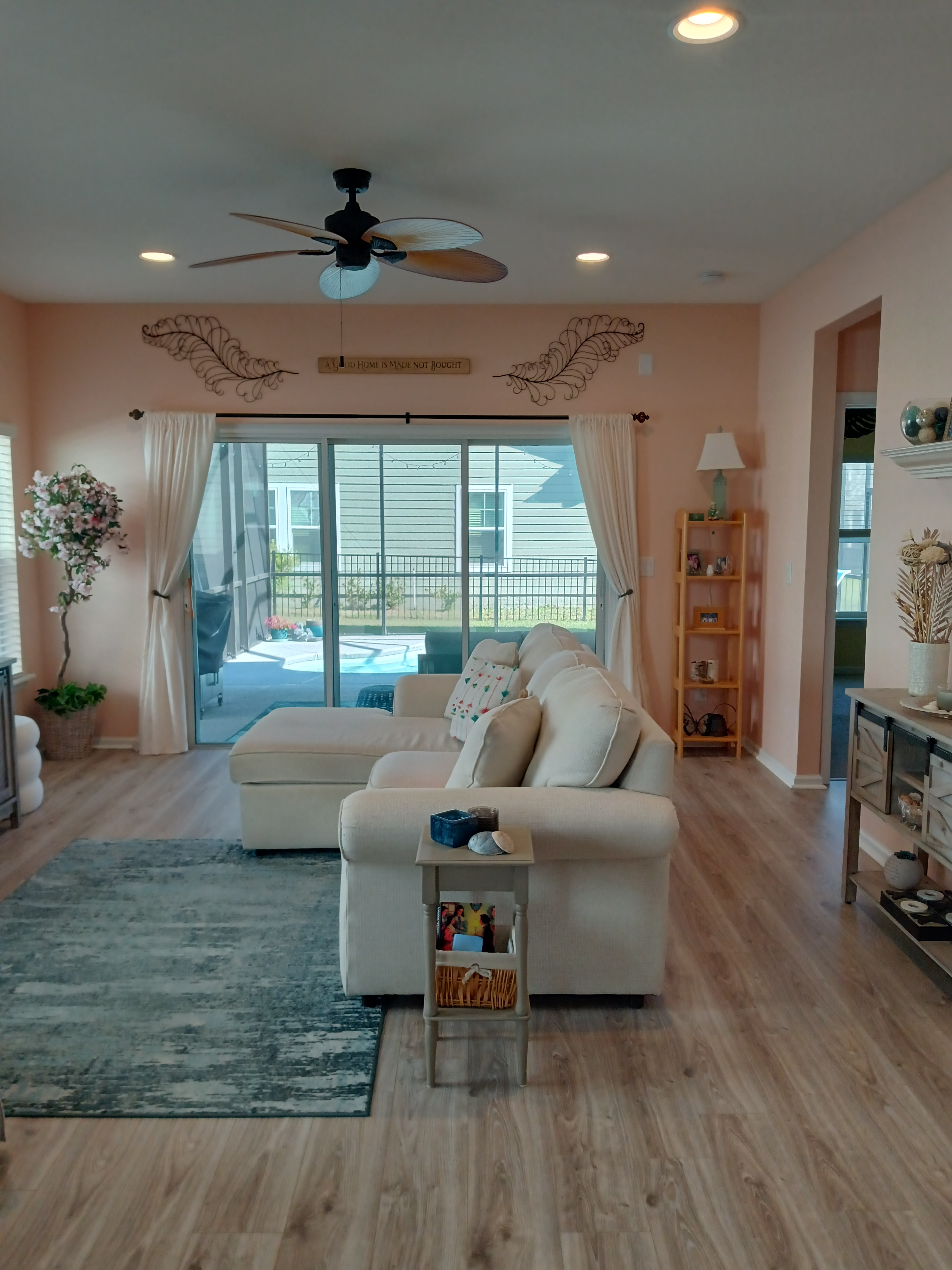 Open living room with peach walls, sectional sofa, and sliding glass doors