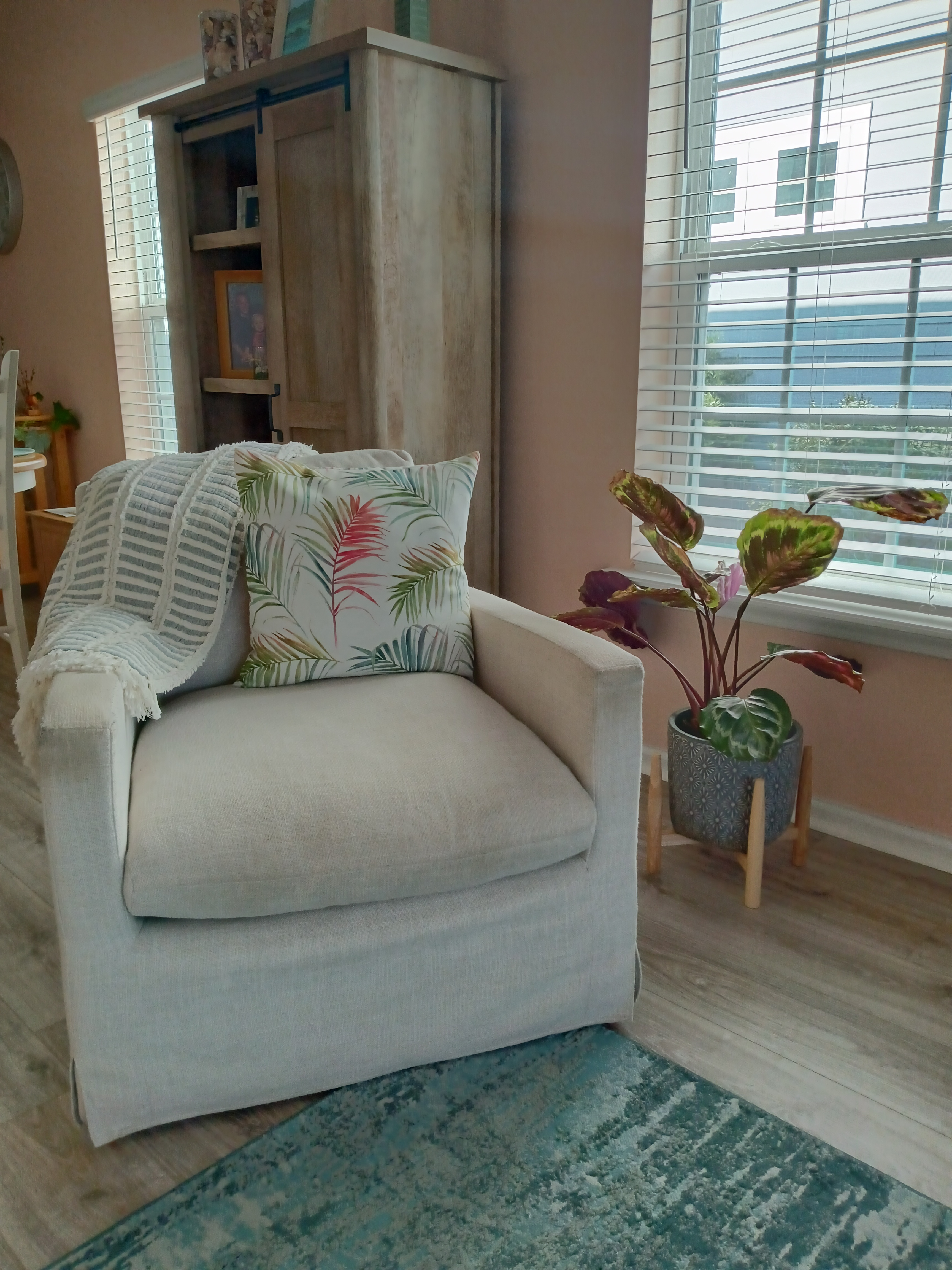 Cozy sitting nook with neutral armchair, tropical pillow, and indoor plant